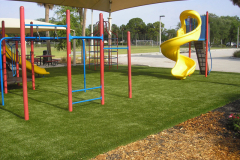 Artificial grass at a playground with jungle gym and slides.