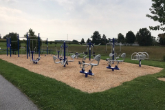 Outdoor fitness equipment pm a sand court at a park.