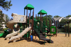 A slide with stairs and a tower with roofs and other toys.