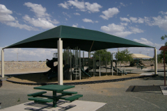 A shaded playground under a pavilion.