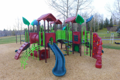 A red blue and yellow playground in a park during fall.
